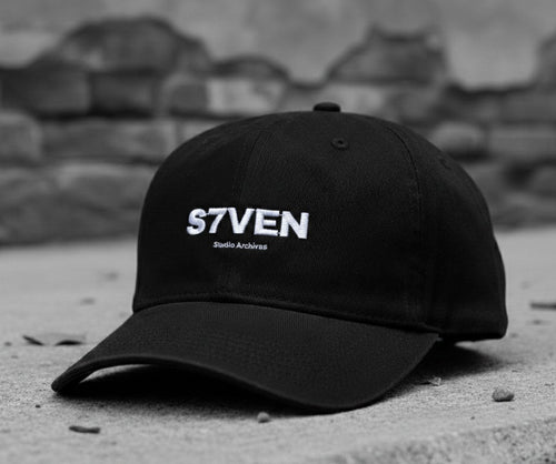 Casquette ajustable S7VEN noire avec logo brodé, vue de face, style streetwear minimaliste.
